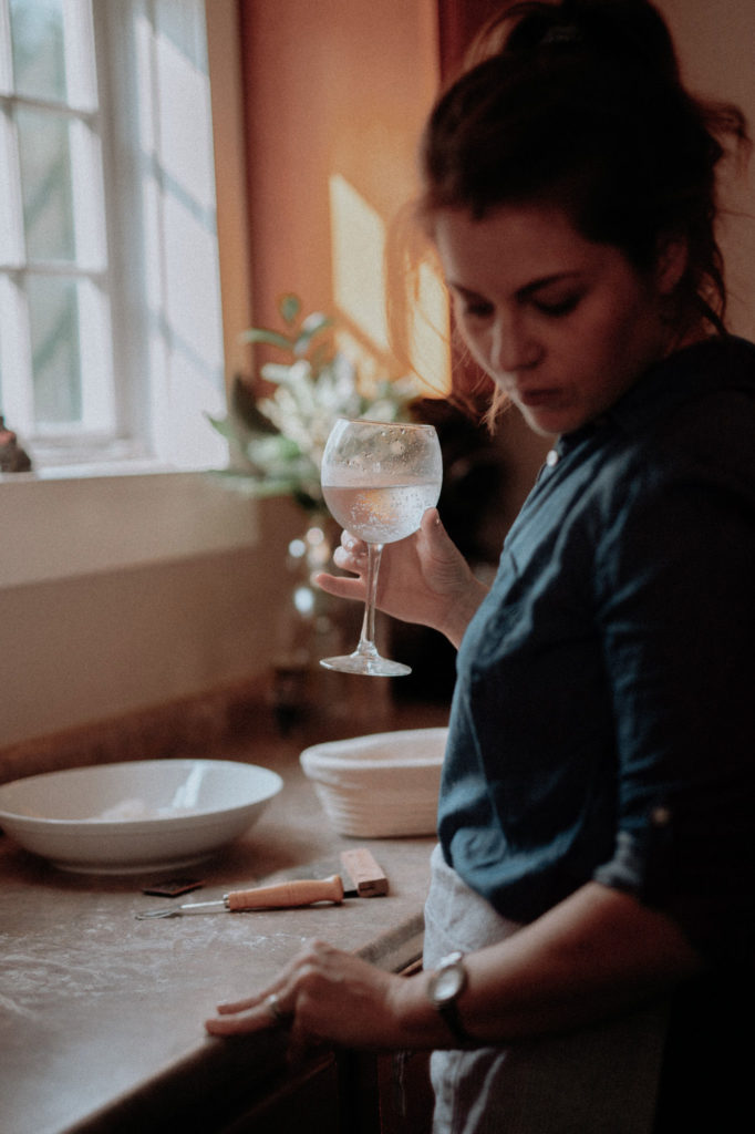 women cooking in kitchen drinking sparkling water out of wine glass