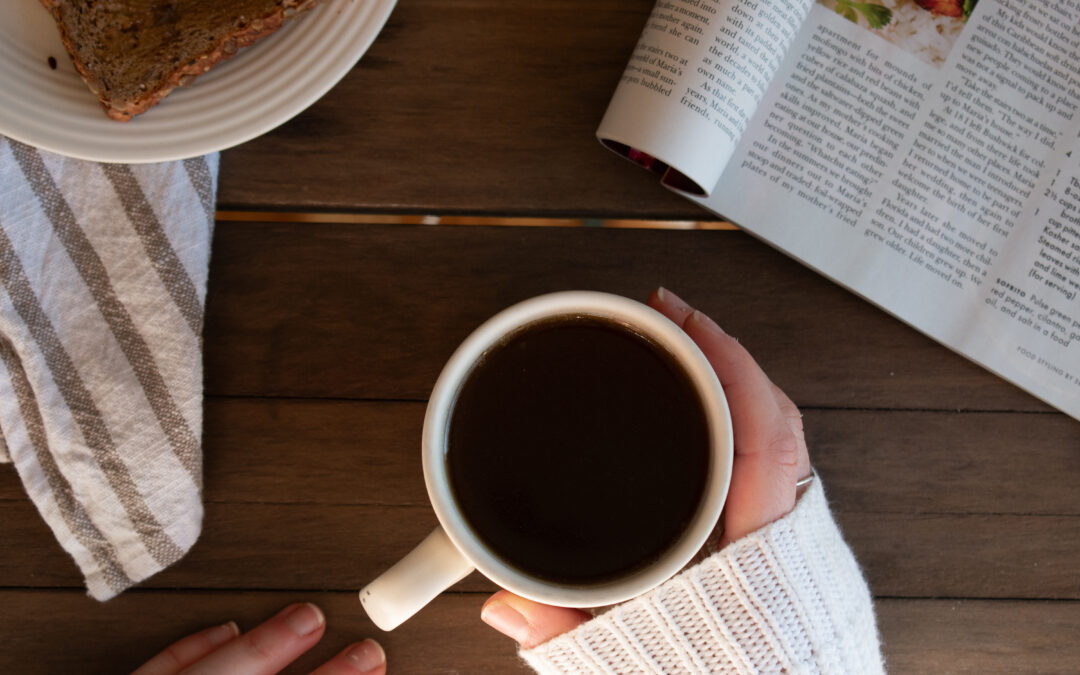 overhead shot of cup of bone broth heals by hand with a nearby magazine