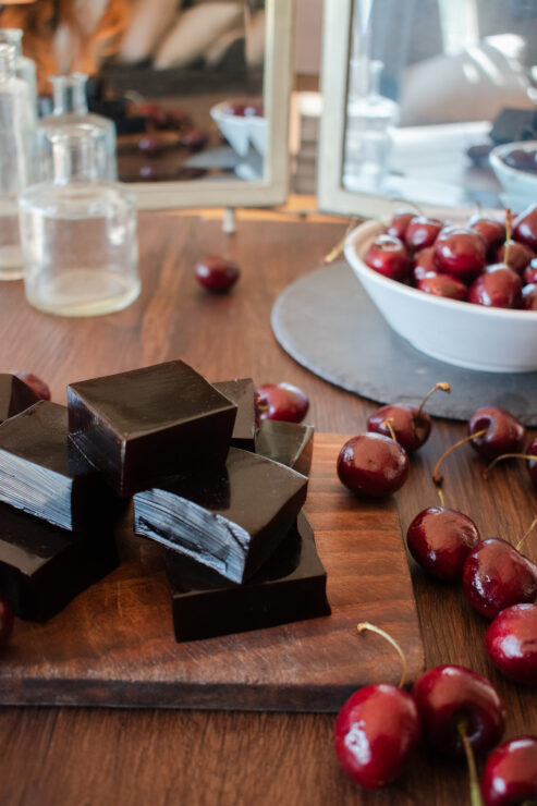 gummies stacked up on wood board with cherries surround