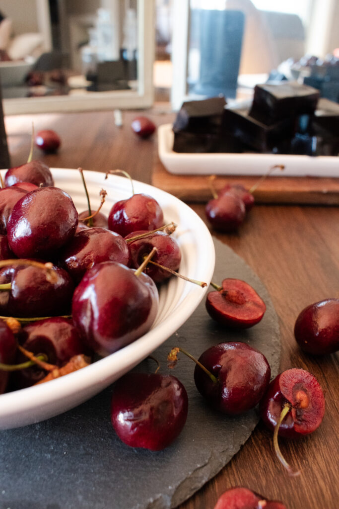 bowl of cherries with gummies in background and reflection on mirror