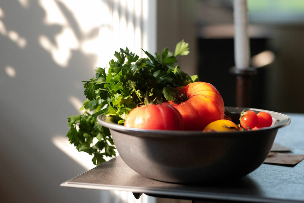 bowl of fresh tomatoes and herbs with light coming in from window 
