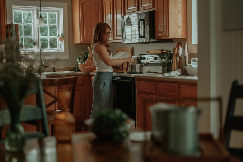 distance shot of girl cooking in kitchen with a recipe book in her hand 