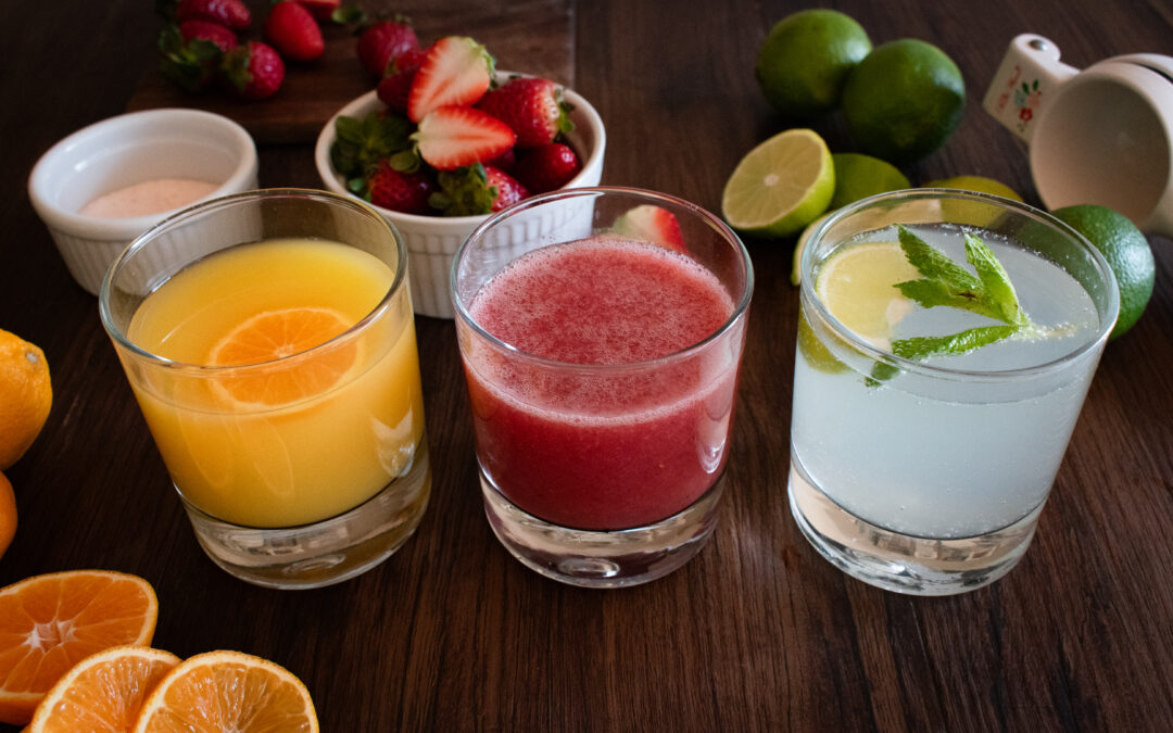 3 different colorful drinks in short glasses on a dark background