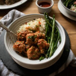 table with Bol of meatballs, rice and green beans with a fork in it