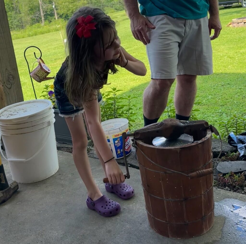 Girl churning ice cream in old fashioned ice cream maker