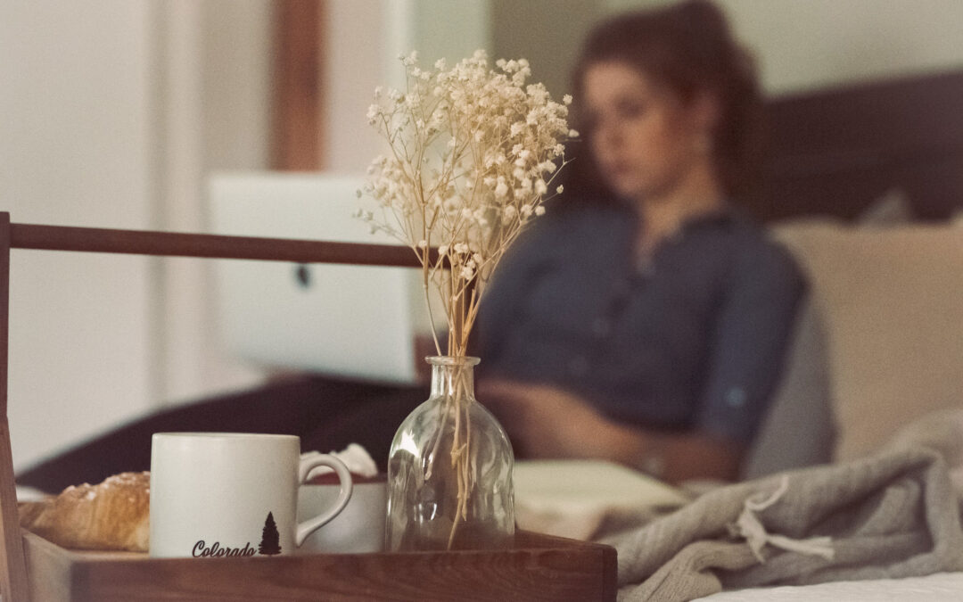 girl sitting on bed with laptop behind a bouquet of flowers