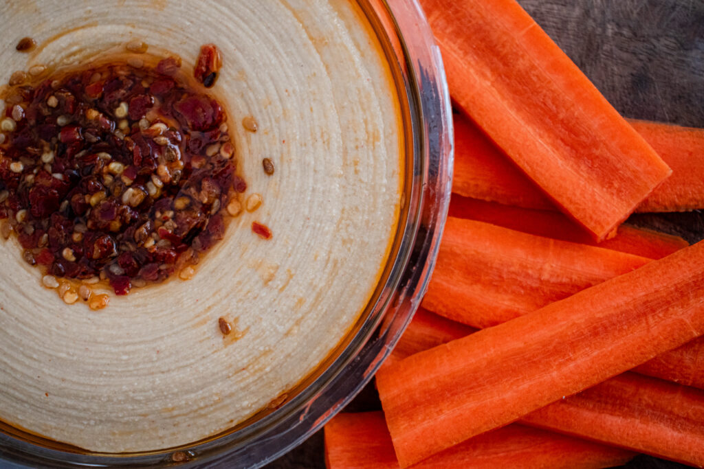 overhead show of hummus with some carrot sticks