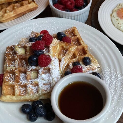 shot of breakfast scape of waffles and maple syrup and berries