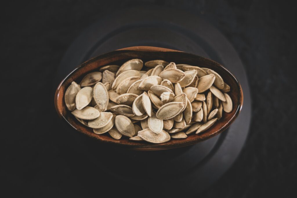 overhead shot of a bowl of pumpkin seeds on a dark background