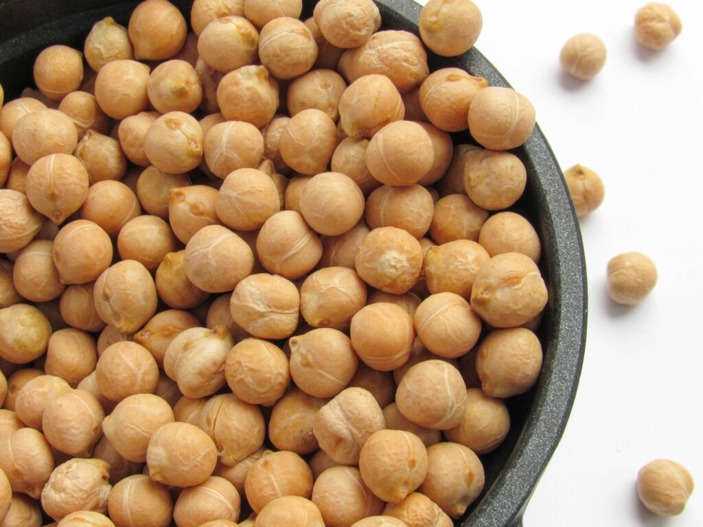 overhead shot of chickpeas in a bowl spilling out onto while background