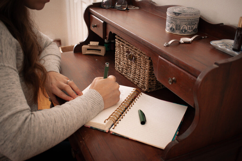 woman writing on a writing desk in a journal 