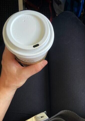 overhead shot of a lap holding a latte travel cup on a plane