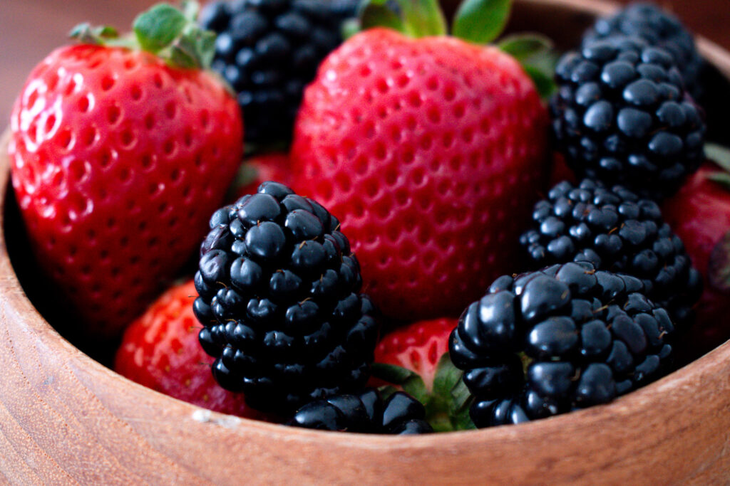 wooden bowl with close up shot of strawberries and blackberries