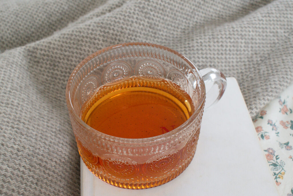 cup of tea stacked on books that are on a bed