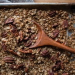 sheet pan of pecan granola with a spoon in it