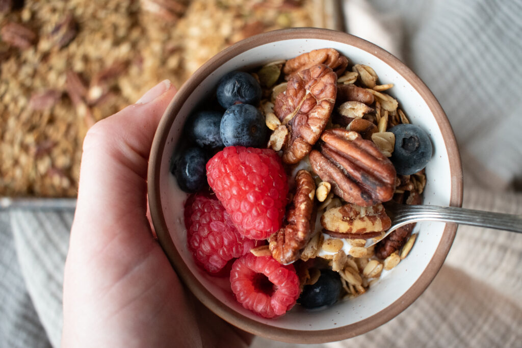 hand holding a bowl of granola and fresh berries