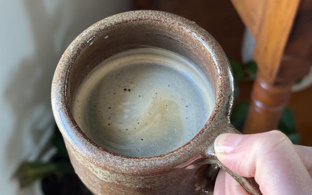 hand holding brown mug of mushroom coffee