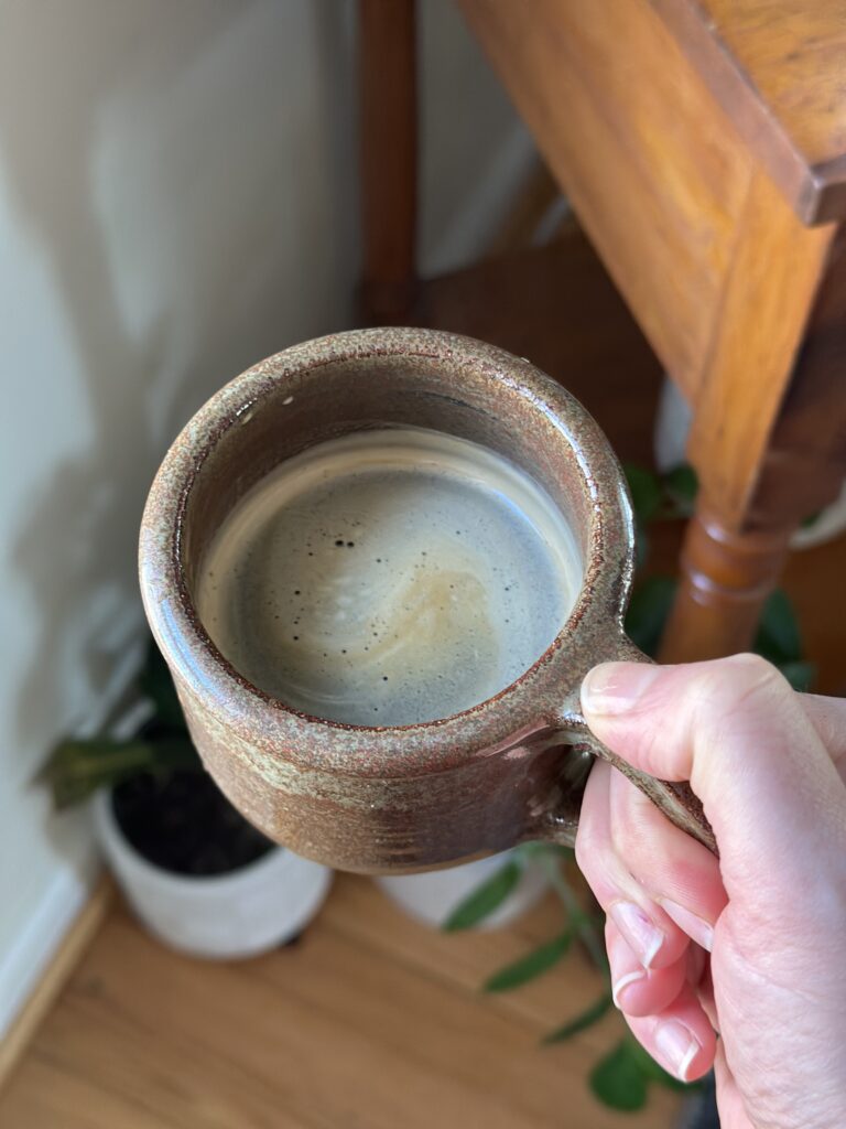 hand holding brown mug of mushroom coffee